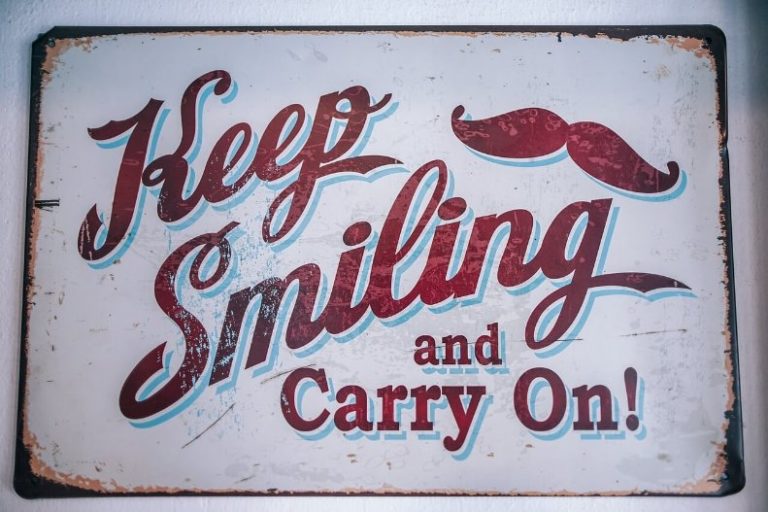 Positive energy sign that says keep smiling and carry on